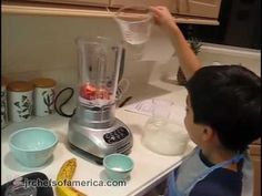 a little boy that is standing in front of a blender