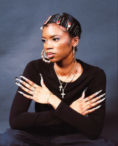 a woman with her hands on her chest posing for the camera, wearing black and silver nails