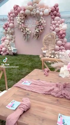 a wooden table topped with pink and white balloons