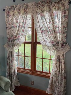 a living room with a chair, window and curtain in it's center area