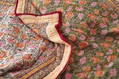 an old quilt is laying on top of the bedding with red and yellow flowers