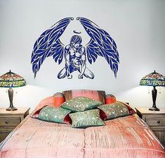 a bed with two lamps on either side and an angel wall decal above it