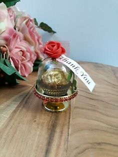 there is a small glass bell with flowers in it on the table next to some pink roses