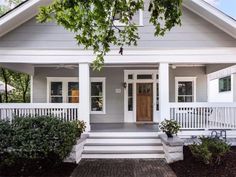 a white house with porches and steps leading to the front door