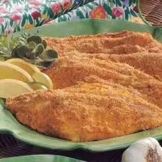 fish fillets on a green platter with lemons and garlic