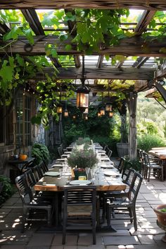 an outdoor dining area with wooden tables and chairs under a pergolated roof, surrounded by greenery