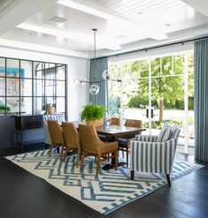 a dining room table and chairs in front of a large window with blue drapes