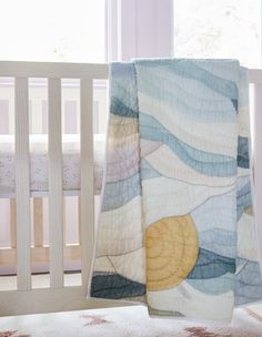 a baby crib with a blanket on top of it and a bed in the background