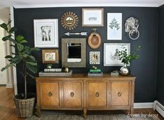 a living room with pictures on the wall and a potted plant next to it