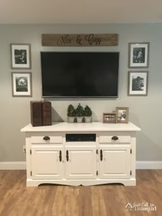 a white entertainment center with pictures on the wall and a flat screen tv mounted above it