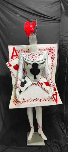 a white statue holding a red heart and playing cards on it's chest with the letter a in front of it