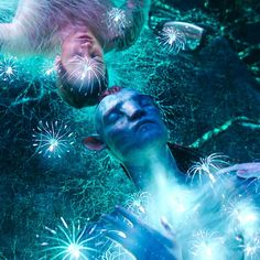 two people with blue paint on their faces are swimming in the water and surrounded by fireworks