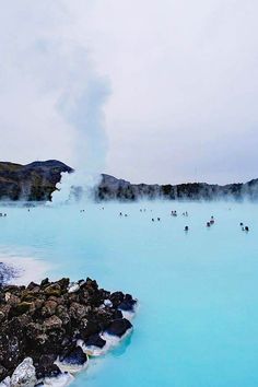 people are swimming in the blue lagoon with steam coming out of it's water