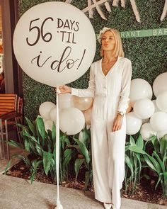 a woman standing in front of a sign with balloons