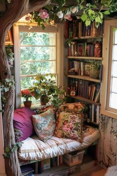 a window seat with bookshelves and pillows on it in front of a tree