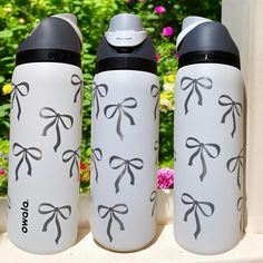 three white and black water bottles with bows on them