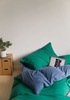 a bed with green sheets and blue pillows