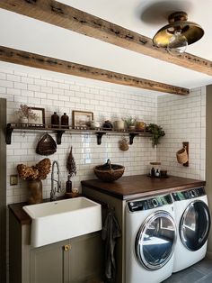 a washer and dryer in a small room with exposed wood beams on the ceiling