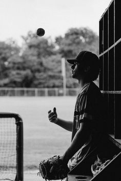 black and white photograph of a young boy throwing a ball to another person on a baseball field