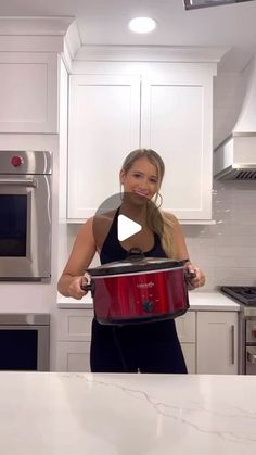 a woman holding a red pot in her kitchen