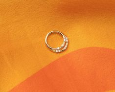 an orange and yellow background with a ring on it's side that has three small white stones in the middle