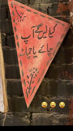 a red triangular sign hanging from the side of a brick wall with writing on it