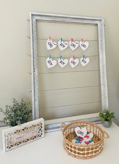 a white table topped with a basket filled with flowers and two small hearts hanging from clothes pins