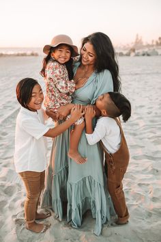 a mother and her two daughters hugging each other on the beach