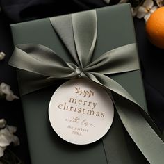 a christmas present wrapped in green paper with a silver bow and ribbon around it next to an orange