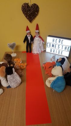 there is a red carpet on the floor with stuffed animals in front of it and a sign that says here comes the bride