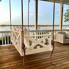 a white porch swing sitting on top of a wooden deck