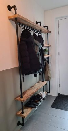 a coat rack with coats and shoes on it in a hallway next to a door