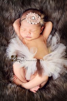 a newborn baby wearing a white tutu and headband