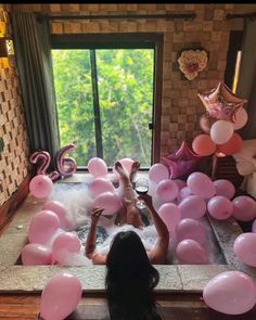 a woman laying in a bathtub surrounded by balloons