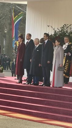 several people are standing on steps in front of flags and other dignitaries at the ceremony