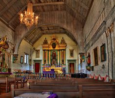 an old church with wooden pews and chandeliers