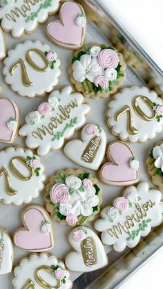 decorated cookies are arranged on a table with name tags and flowers in gold, pink, and green