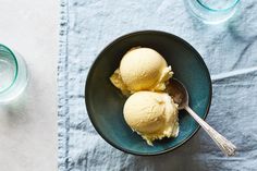 two bowls filled with ice cream on top of a blue table cloth next to water glasses