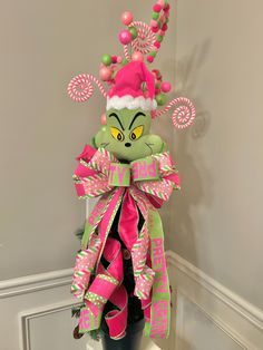 a green and pink elf hat with candy canes on it's head sitting on top of a shelf