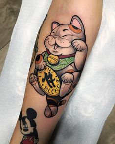 a person with a mickey mouse tattoo on their arm, holding a clock in his hand