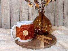 there is a coffee cup and mug coziet on the tray with cinnamon sticks