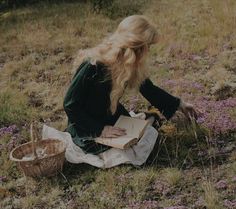 a woman sitting on the ground with a box in her hand and flowers around her