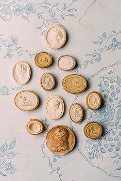 several different types of buttons on a blue and white wallpapered surface with floral designs