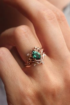 a close up of a person's hand with a green ring on their finger