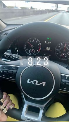 a woman is sitting in the driver's seat of a car with her hands on the steering wheel