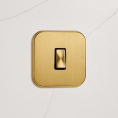 a golden square button on a white marble surface