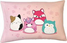 four cartoon animals are sitting on a pink pillow cover with diamond shapes in the background