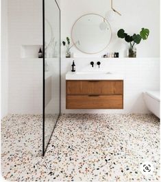 a bathroom with a sink, mirror and bathtub next to a shower head mounted on the wall