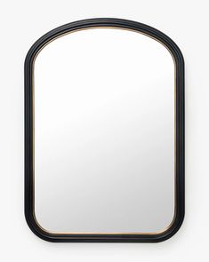 an oval mirror with black frame and gold trim around the edges, hanging on a wall