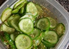 a plastic container filled with sliced cucumbers on top of a granite countertop